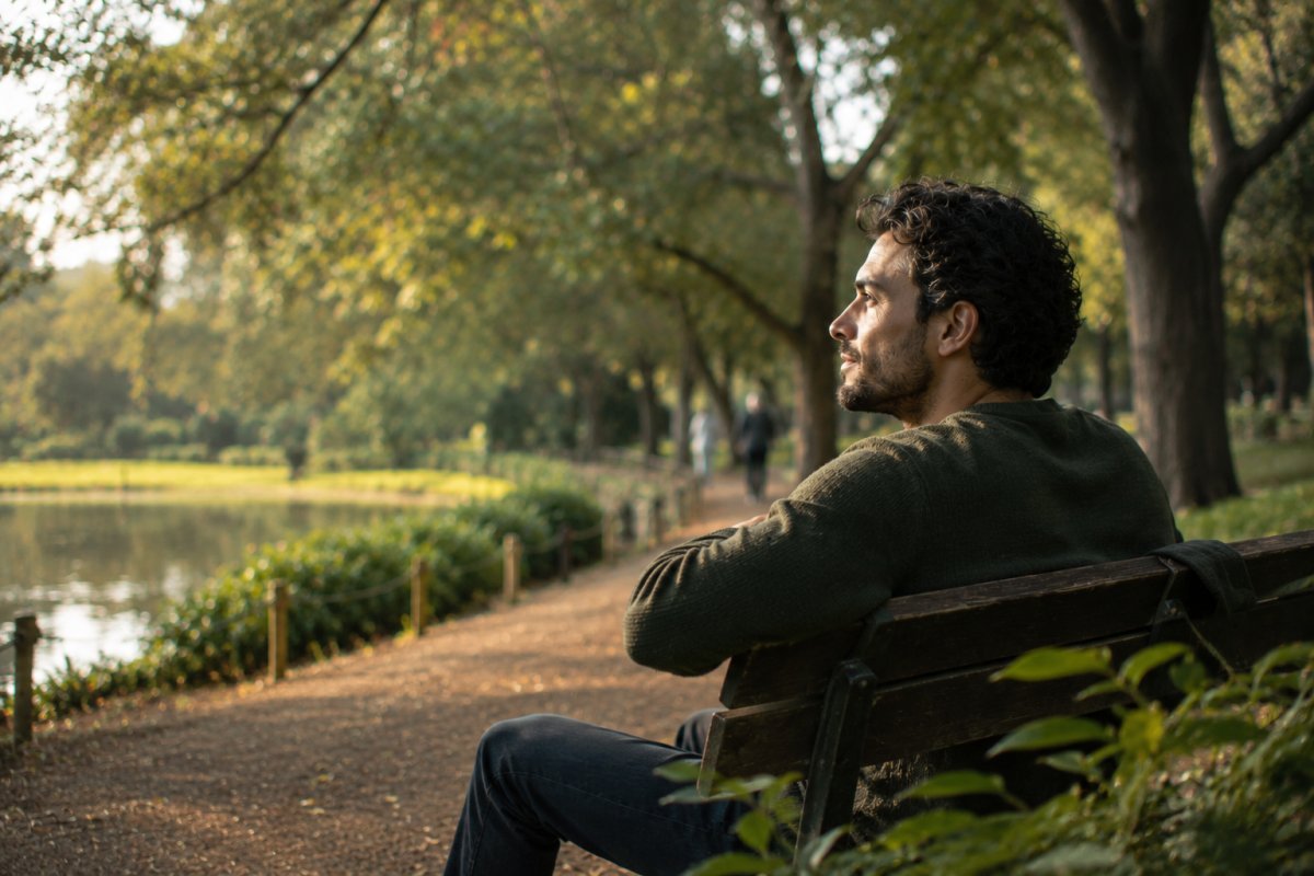 Un hombre reflexionando en un parque rodeado de naturaleza