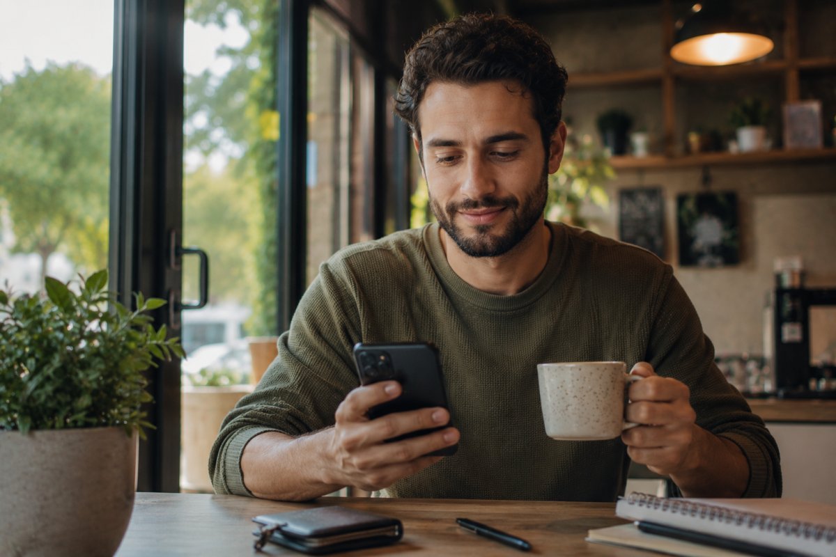 Hombre tranquilo revisando su teléfono mientras toma un café