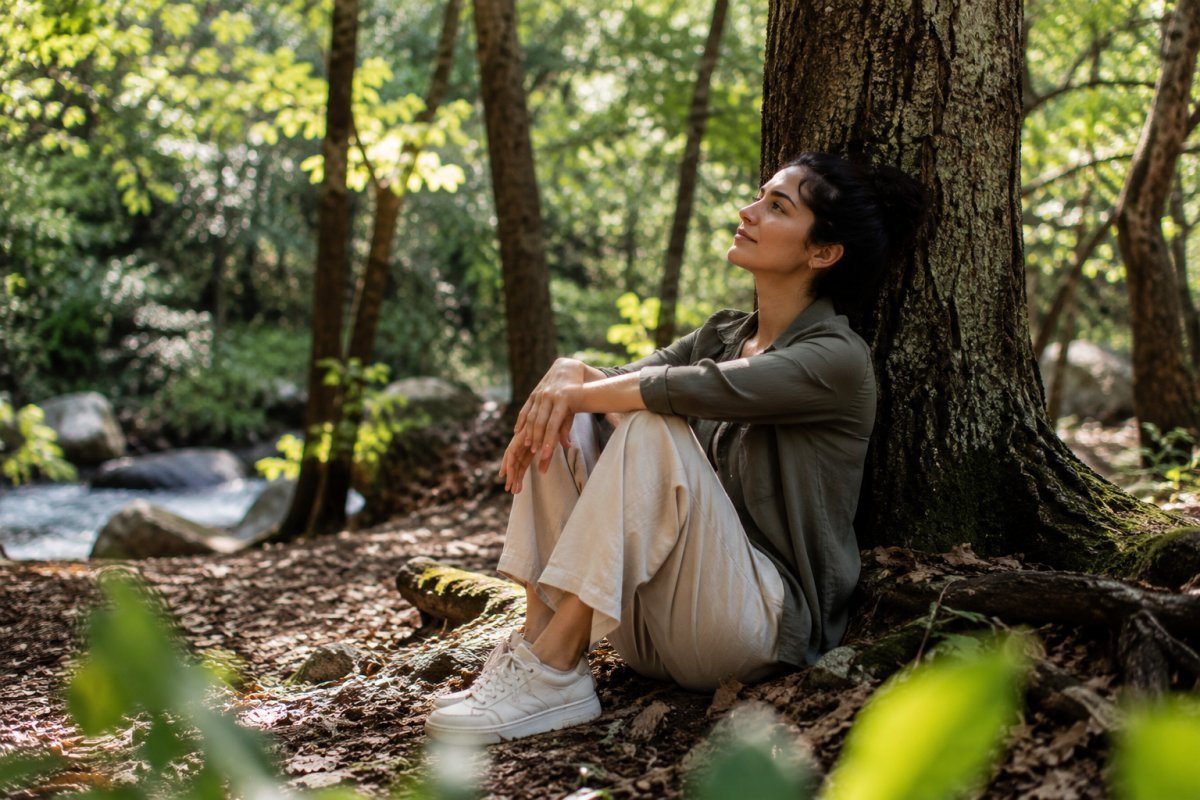 Una mujer reflexionando en la naturaleza, rodeado de árboles